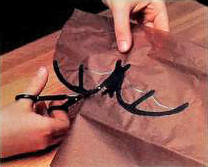 a child's hands are seen cutting out the wings of a paper bat