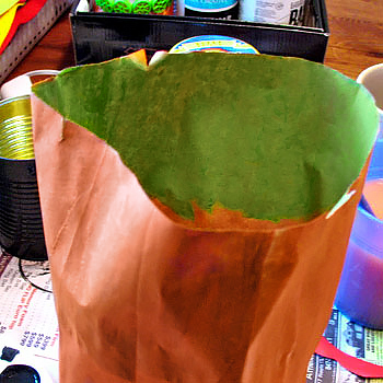 a photo showing an open paper bag, painted orange on the outside and green on the inside
