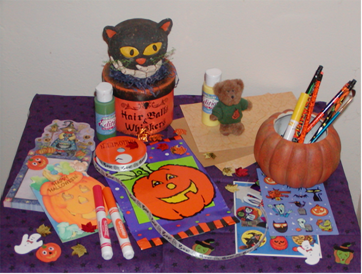 a table with a pile of supplies--paper, stickers, markers, et cetera--for scrapbook-making